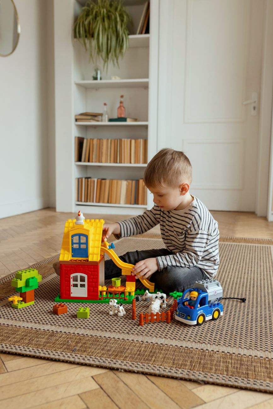 Young boy absorbed in playing with a toy farm set alone on the floor
