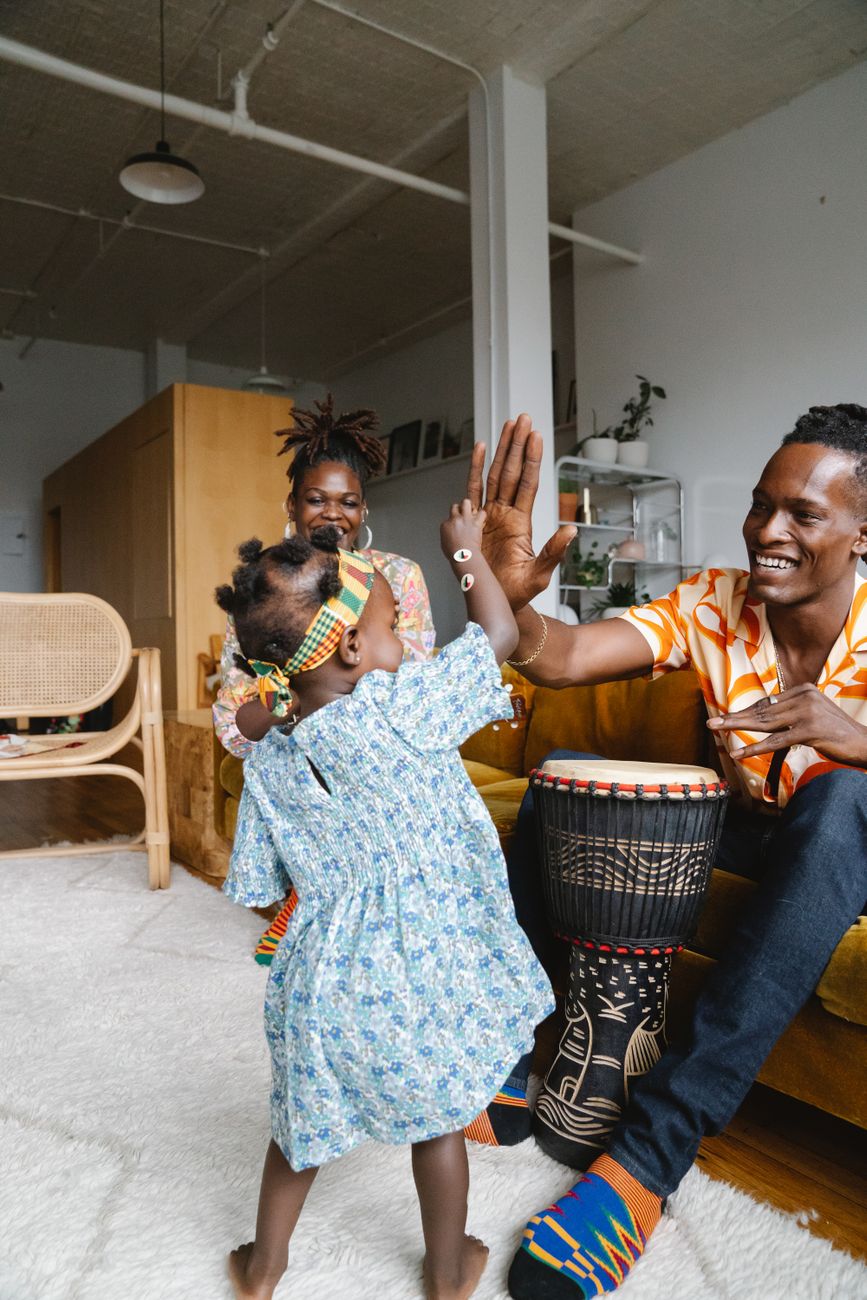 Parents giving their young daughter a happy high-five at home