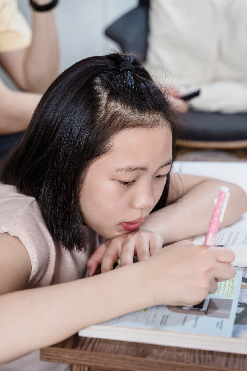 Schoolgirl slumped over her homework, resting her head on her arm