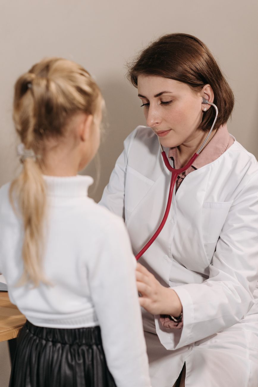 Paediatrician examining a young girl with a stethoscope in a clinic