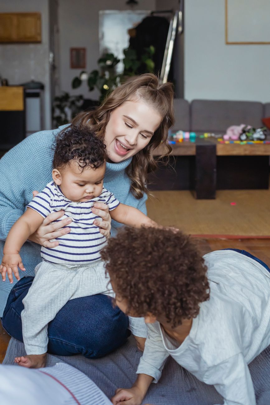 Mother playing and talking with her young children on the living-room floor